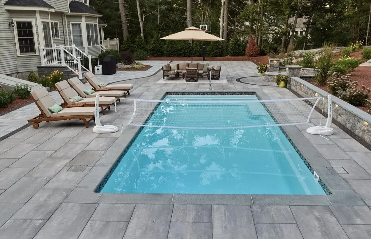 Light paver pool deck with lounge chairs surrounding a rectangular pool